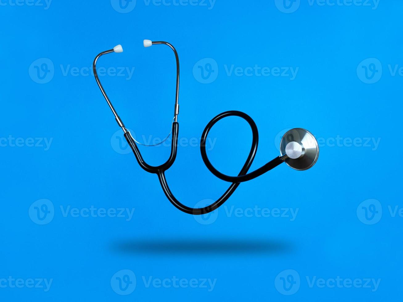 Levitating stethoscope on blue background and shadow under it photo