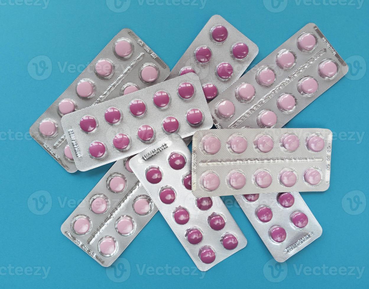 Pink tablets in blisters on blue background photo