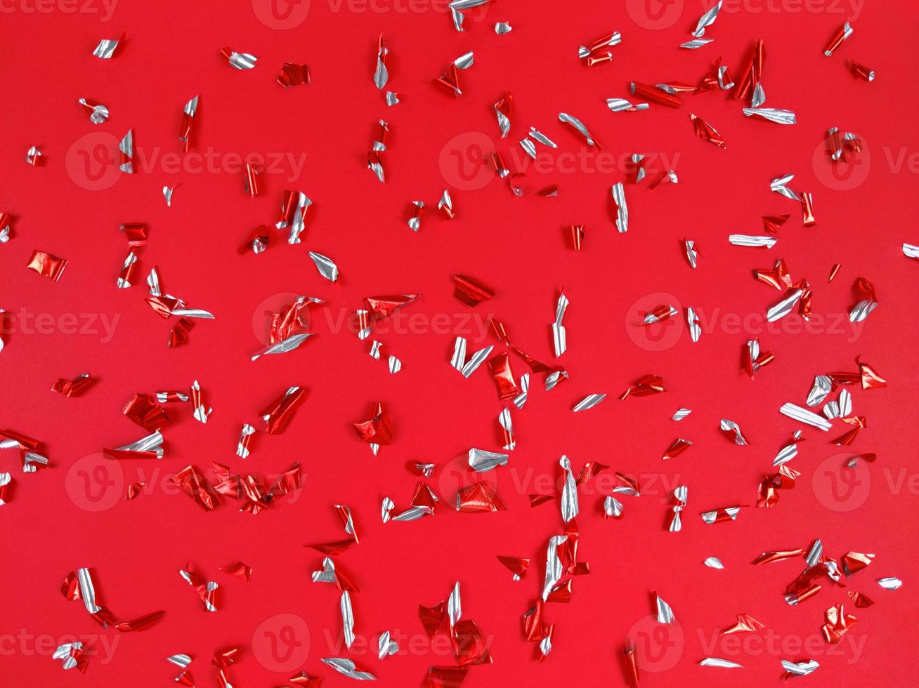 Confetti foil pieces on red background. Abstract festive backdrop. photo