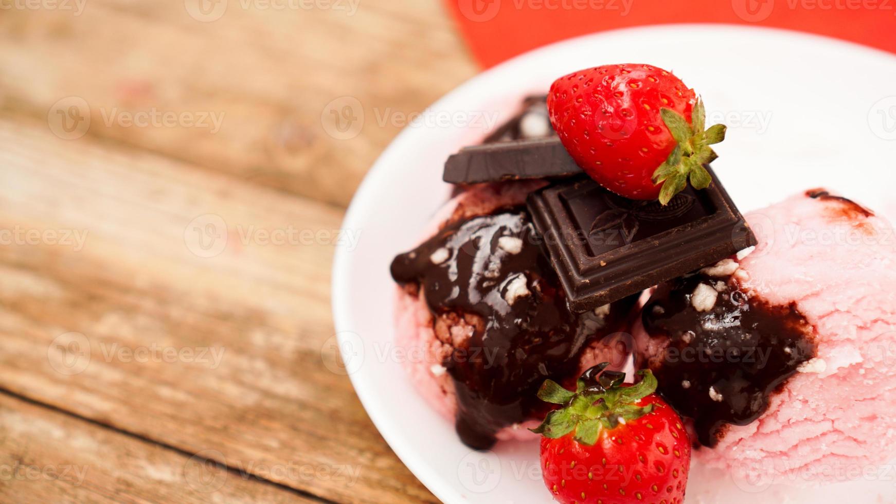 Homemade strawberry ice cream on white plate on a rustic background. photo