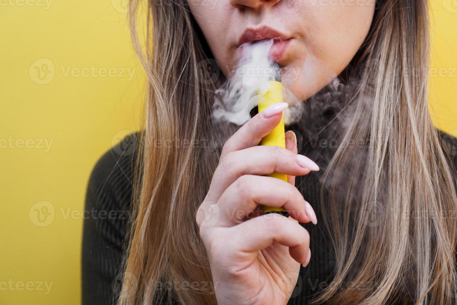 A young girl smokes disposable electronic cigarette photo