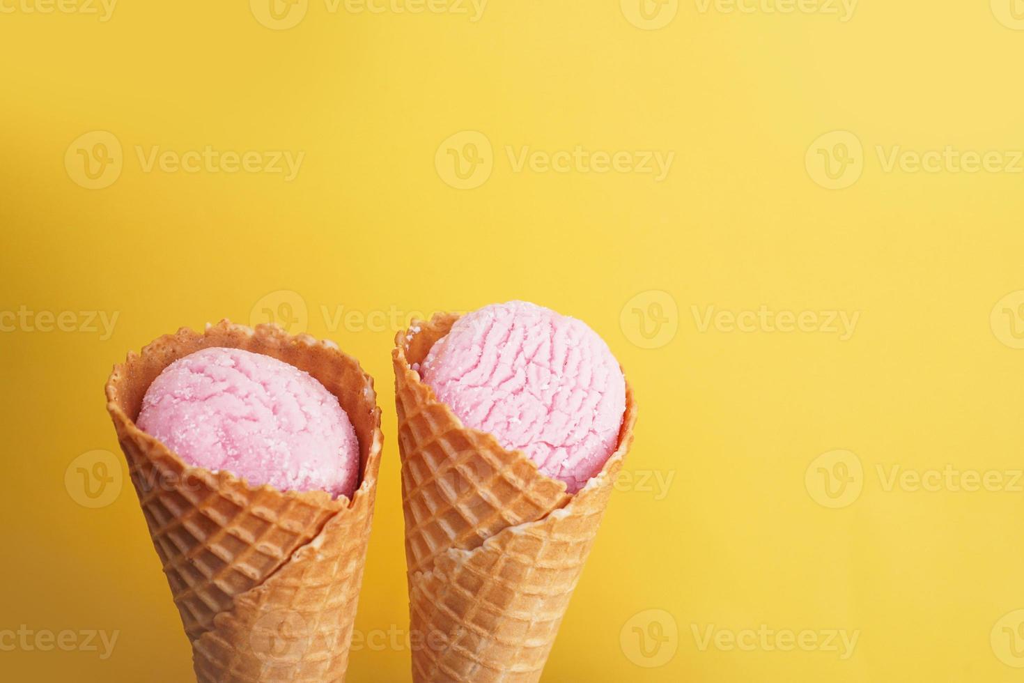 delicioso helado de color rosa en un cono sobre un fondo amarillo. foto