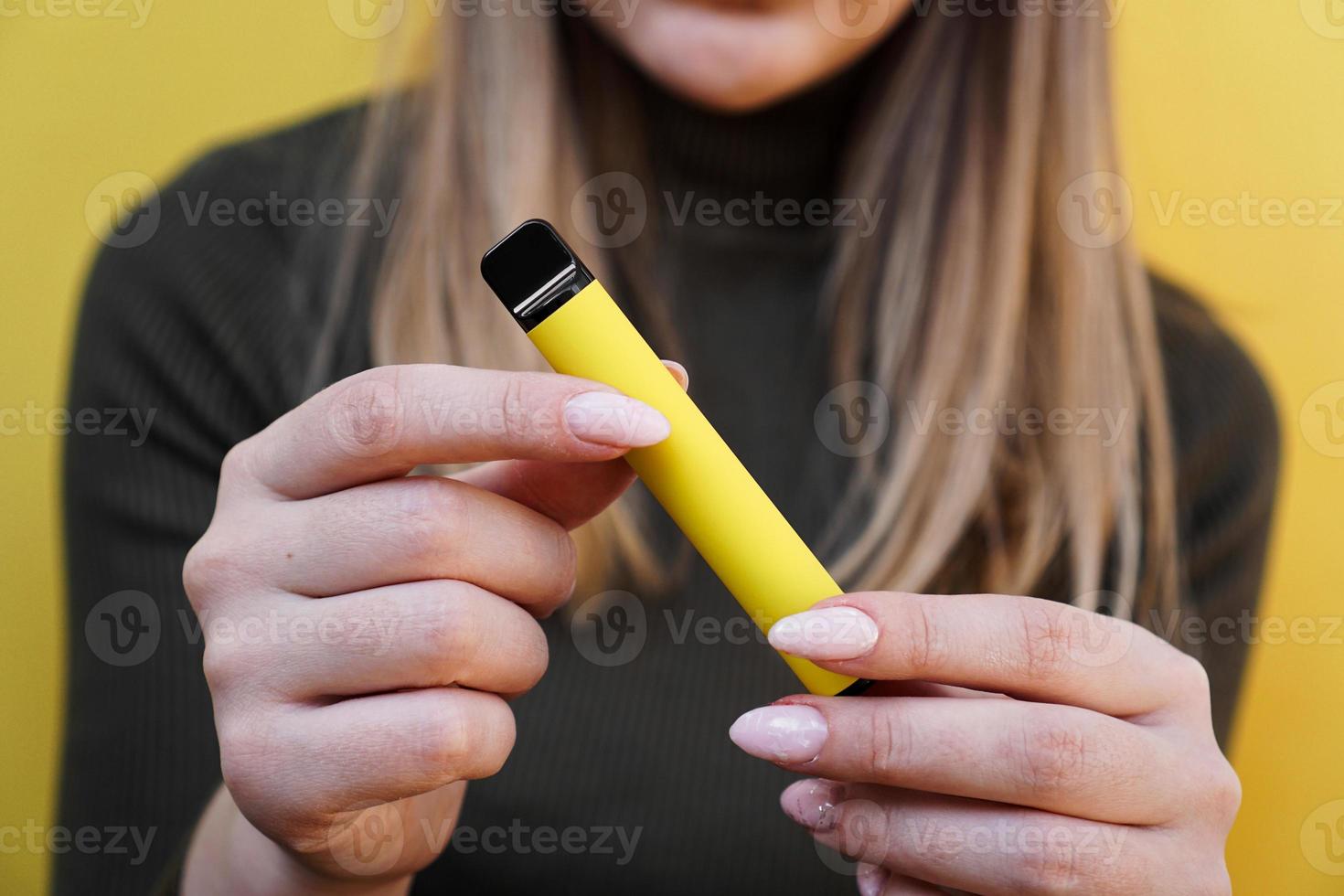 Yellow disposable electronic cigarette in female hand photo