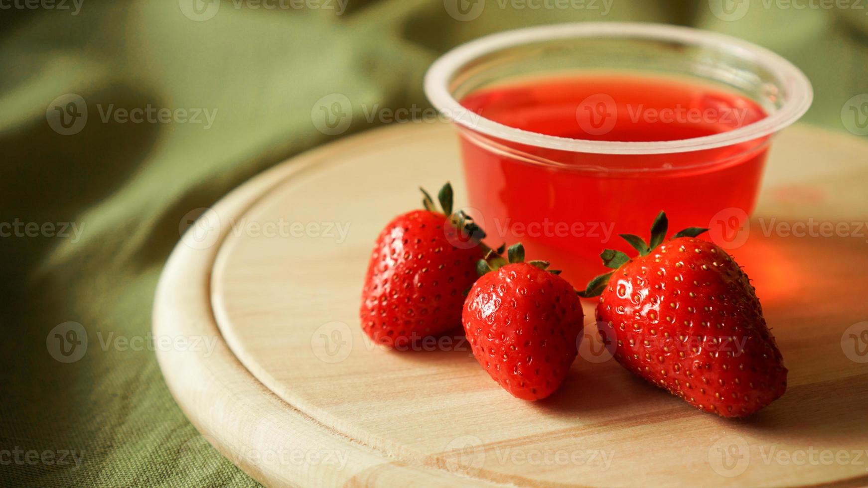 Red strawberry jelly with berries in a plastic container photo