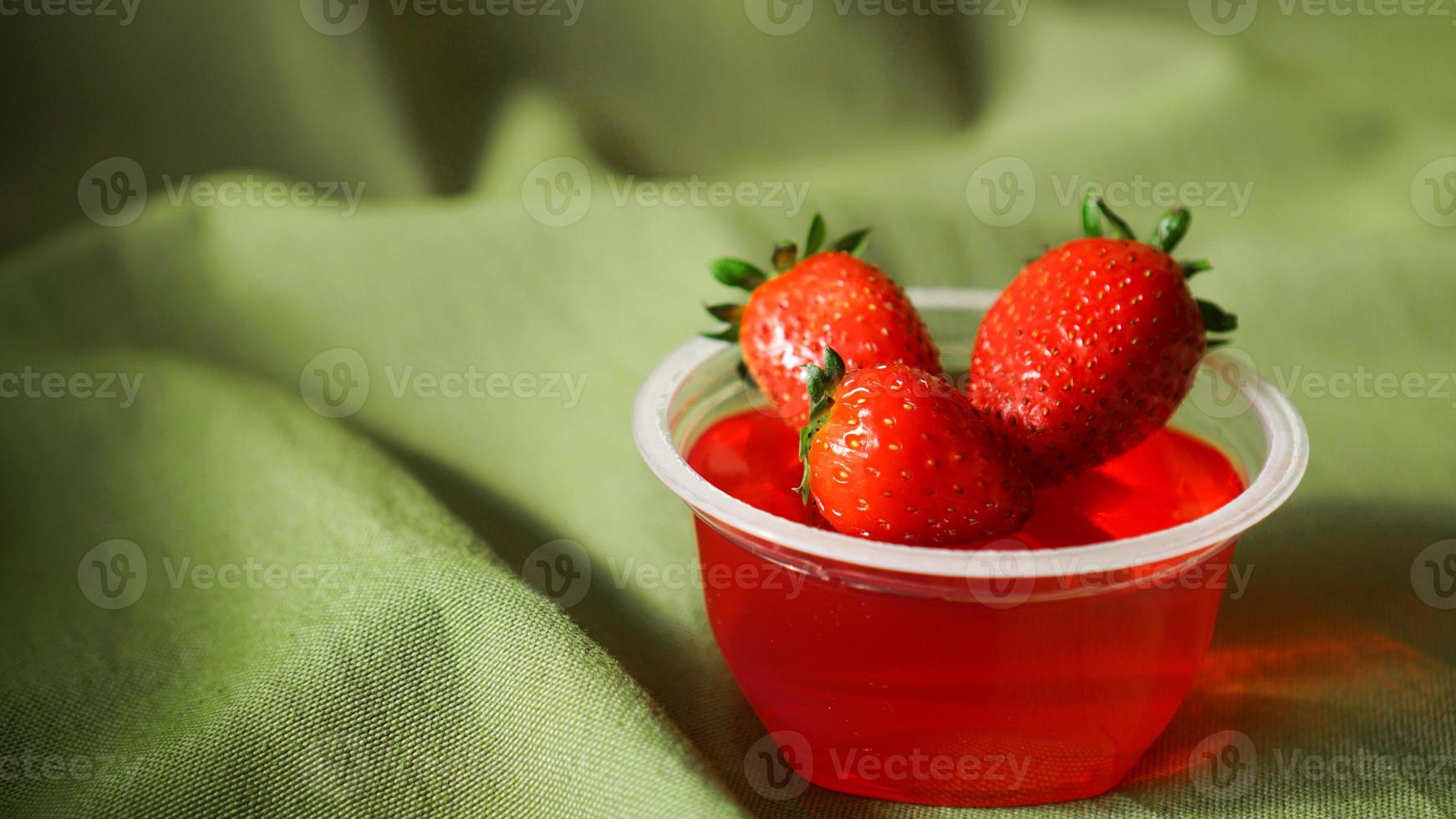 Gelatina de fresa roja con frutos rojos en un recipiente de plástico foto