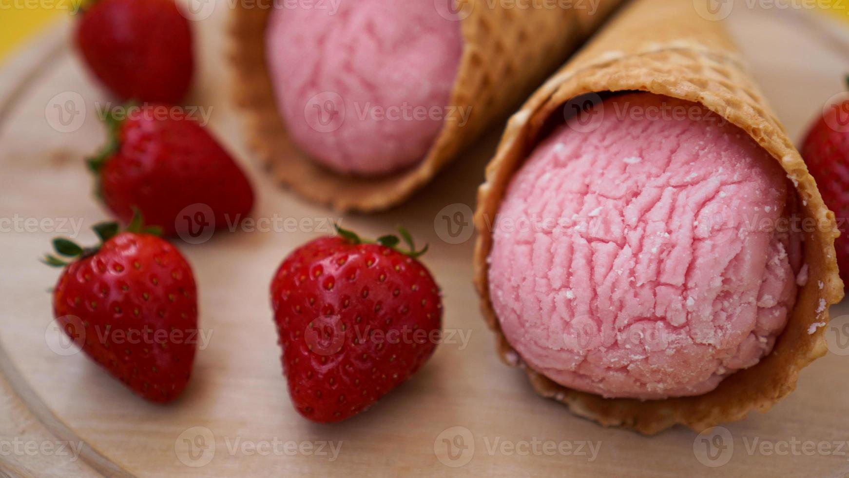 helado de fresa en un cono de galleta. frutos rojos y bolas de helado foto