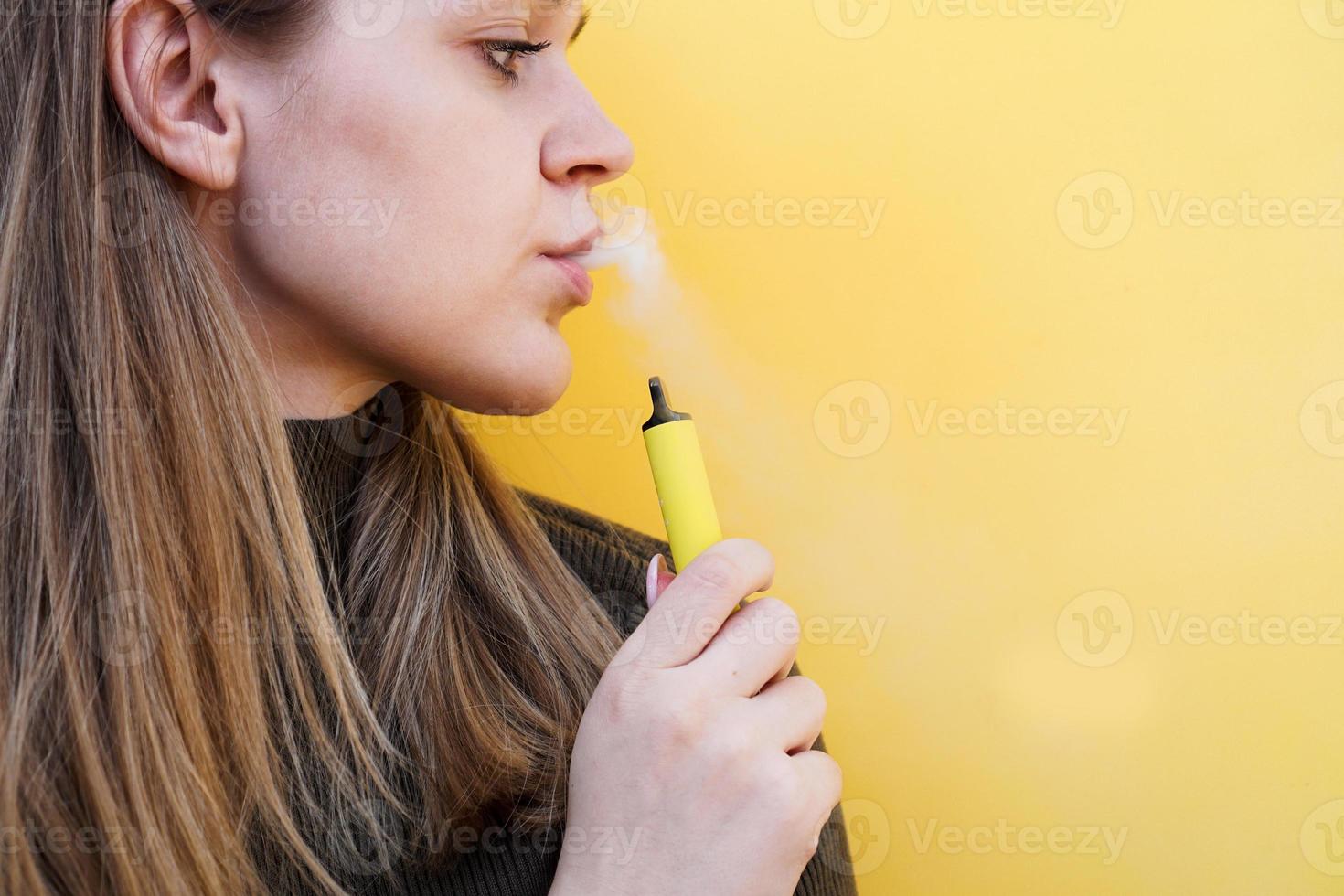 A young girl smokes disposable electronic cigarette photo