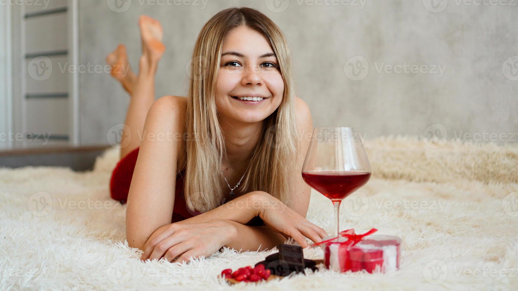 una hermosa rubia sonriente yace en la cama. día de san valentín por la mañana foto