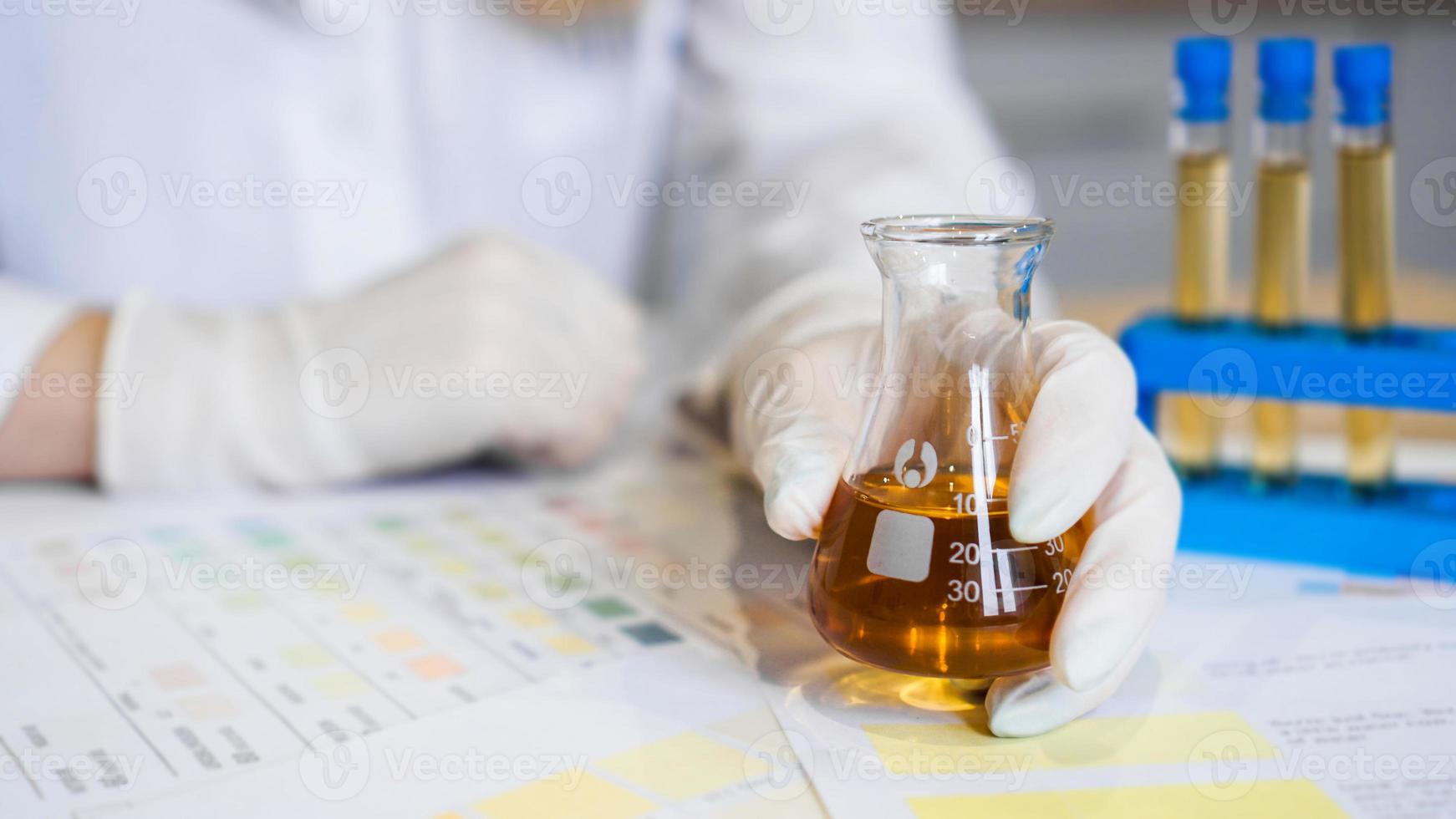 Mujer haciendo análisis de orina con material de ph en laboratorio foto