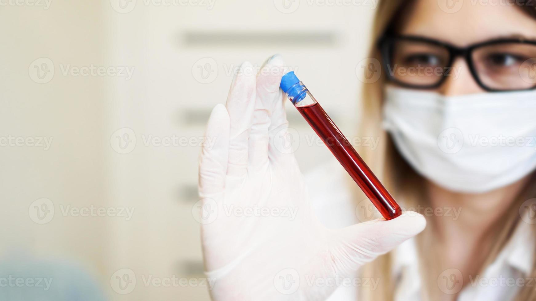 Close up of young female scientist holding test tube with blood sample photo