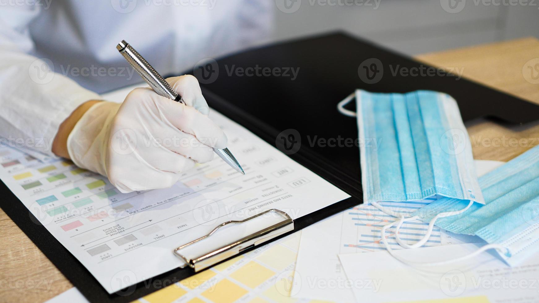 Female doctor filling medical form on clipboard holding ballpoint. photo