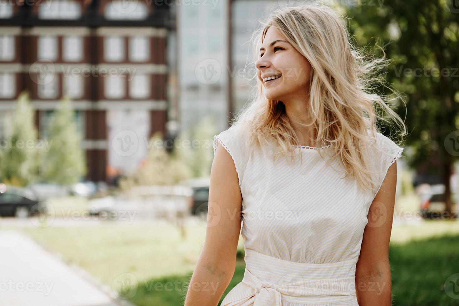 A young blonde in a white dress on the background of a European city photo