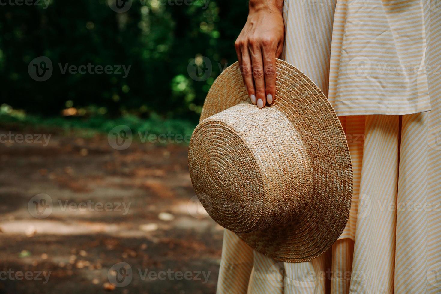 Foto de primer plano de la mano de una mujer sosteniendo un sombrero de paja