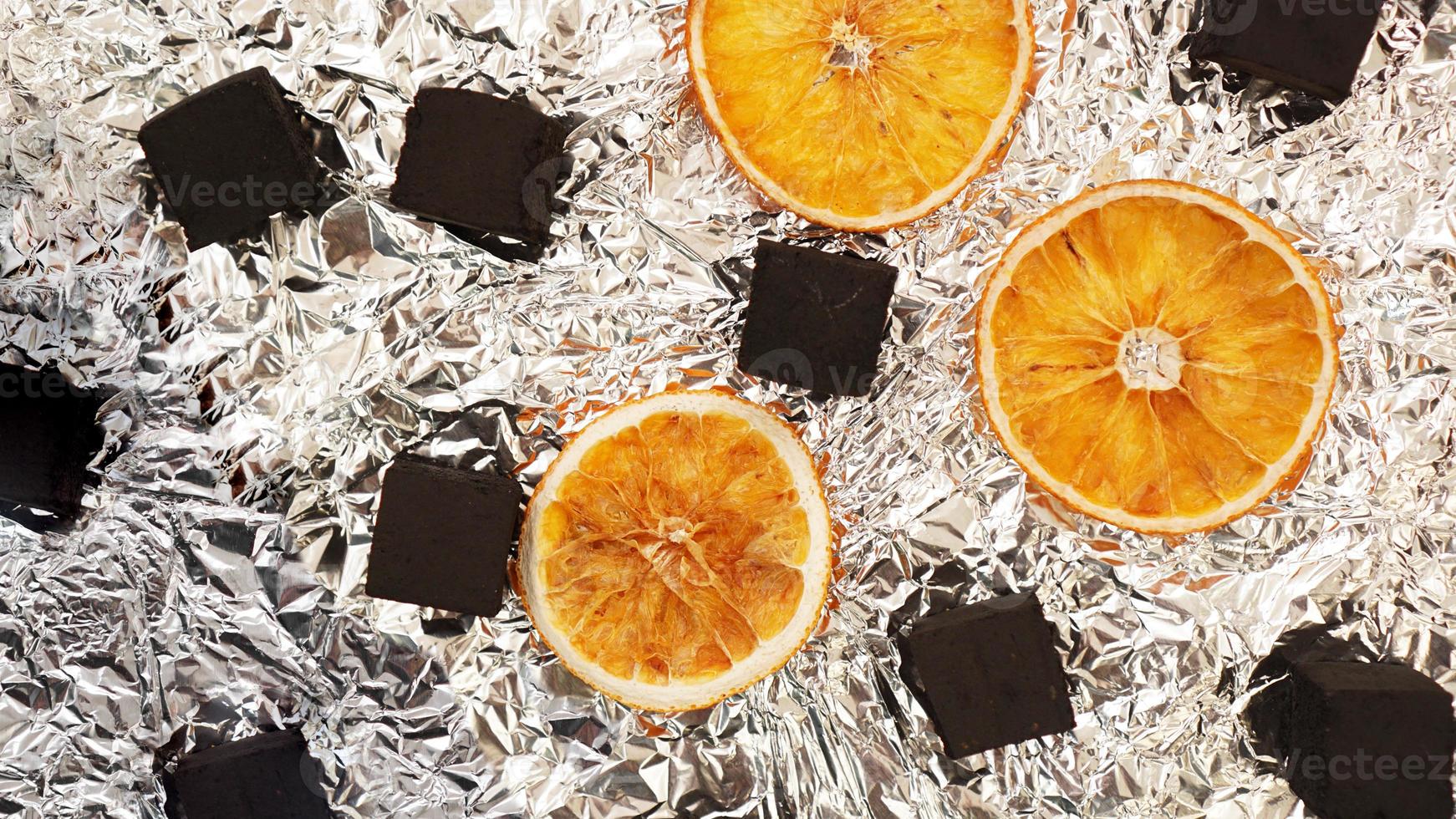 Coals for hookah on foil background with dry oranges photo