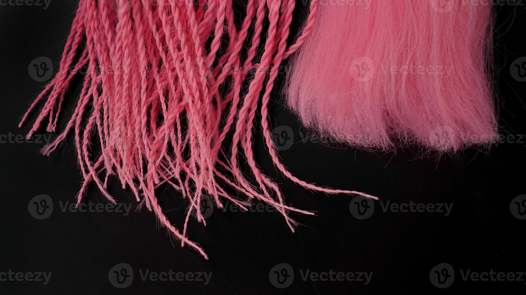 Pink kanekalon hangs on a black background photo