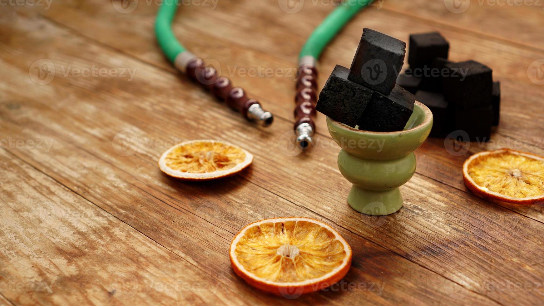 Carbones para narguile sobre fondo de madera con naranjas secas foto