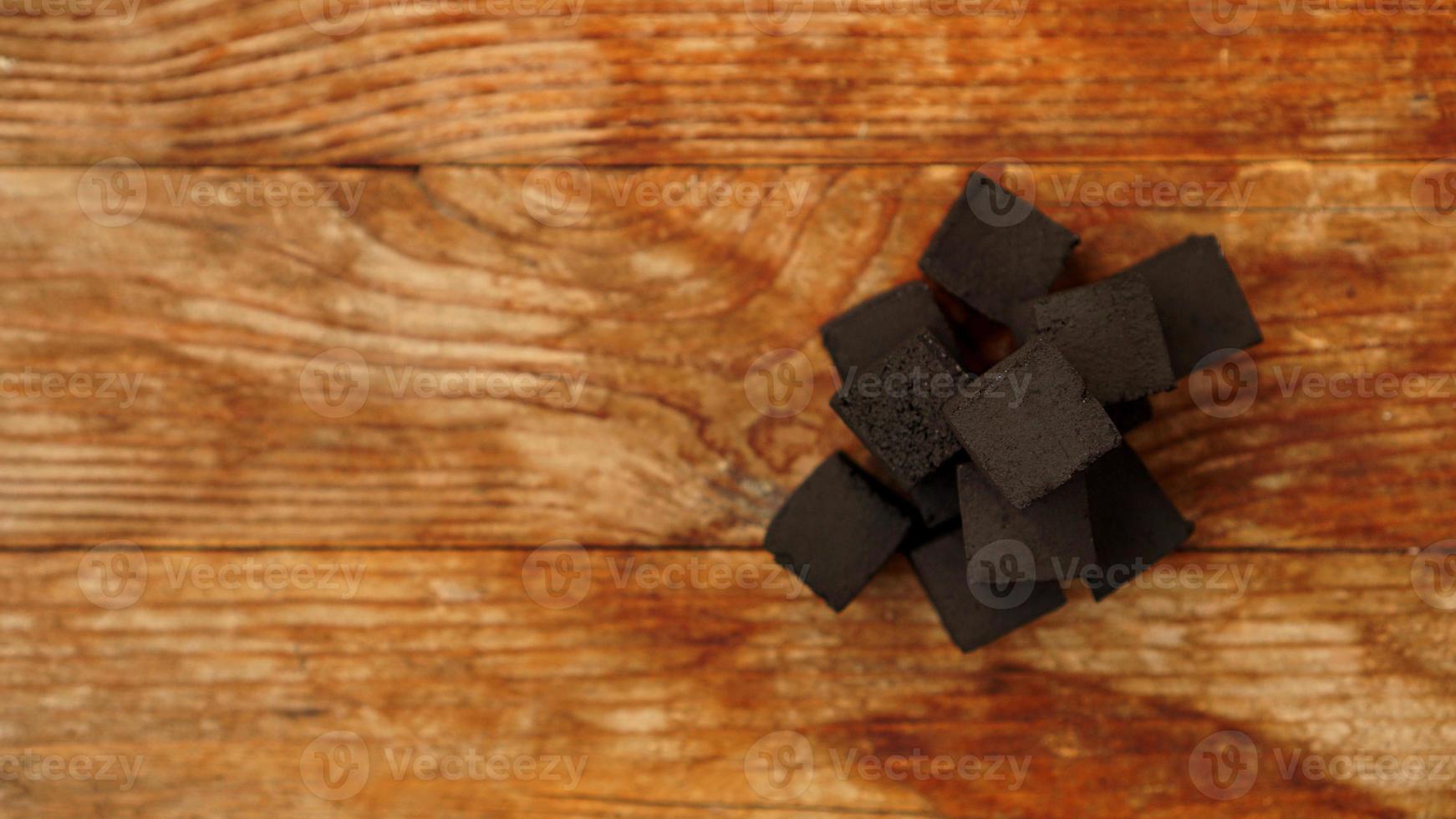 Cubes of coconut coal for hookah on wooden background. photo