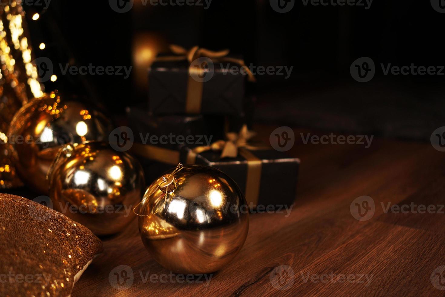 Black gift box with golden ribbon and big gold New Year balls on black photo