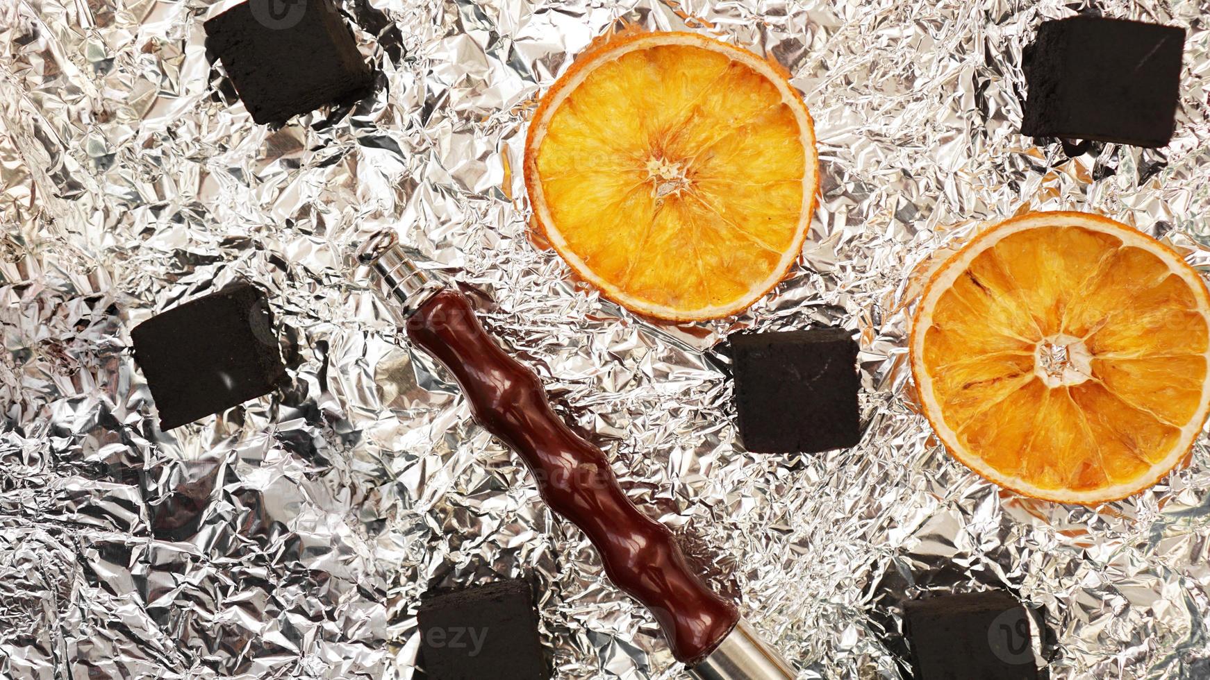 Coals for hookah on foil background with dry oranges photo