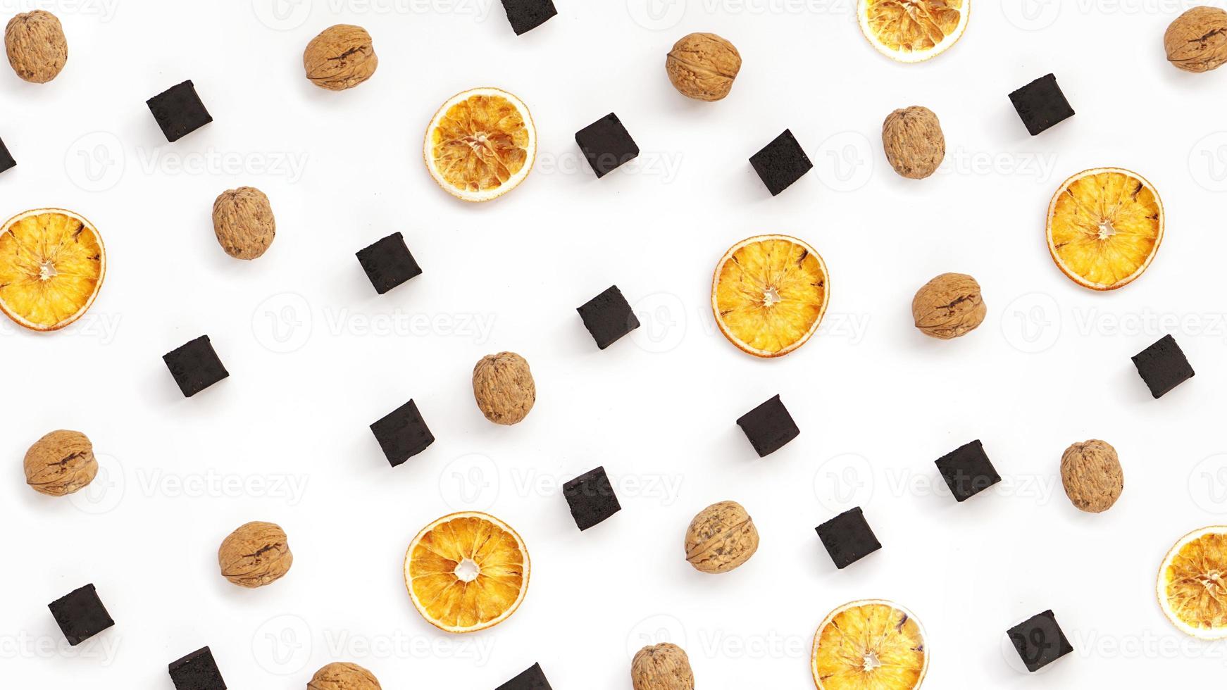 Carbones para narguile con naranjas secas y nueces sobre fondo blanco. foto
