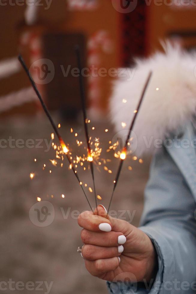 manos femeninas sostienen bengalas encendidas. mujer al aire libre foto