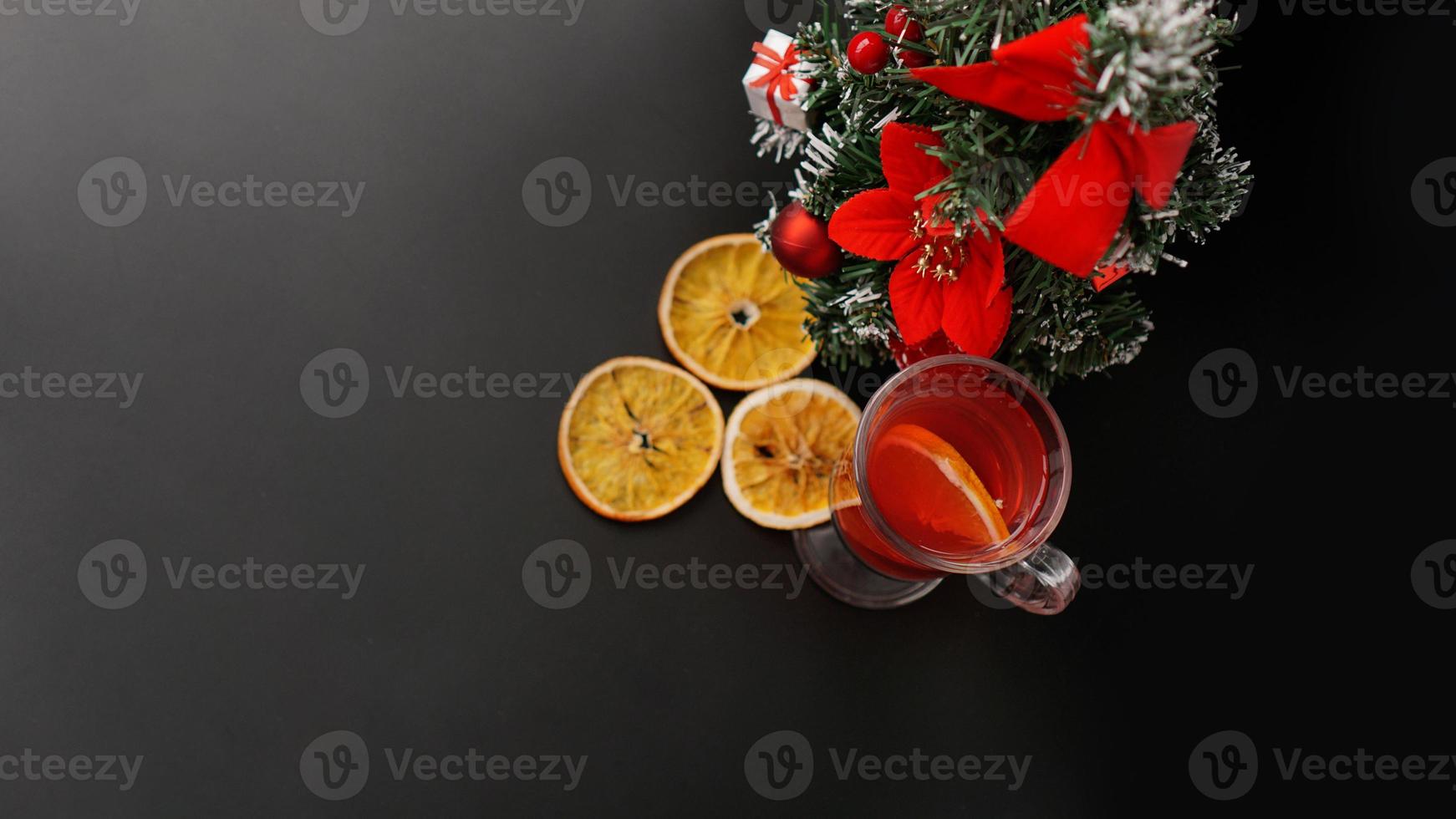 Mulled wine in glass on black table with New year decoration photo