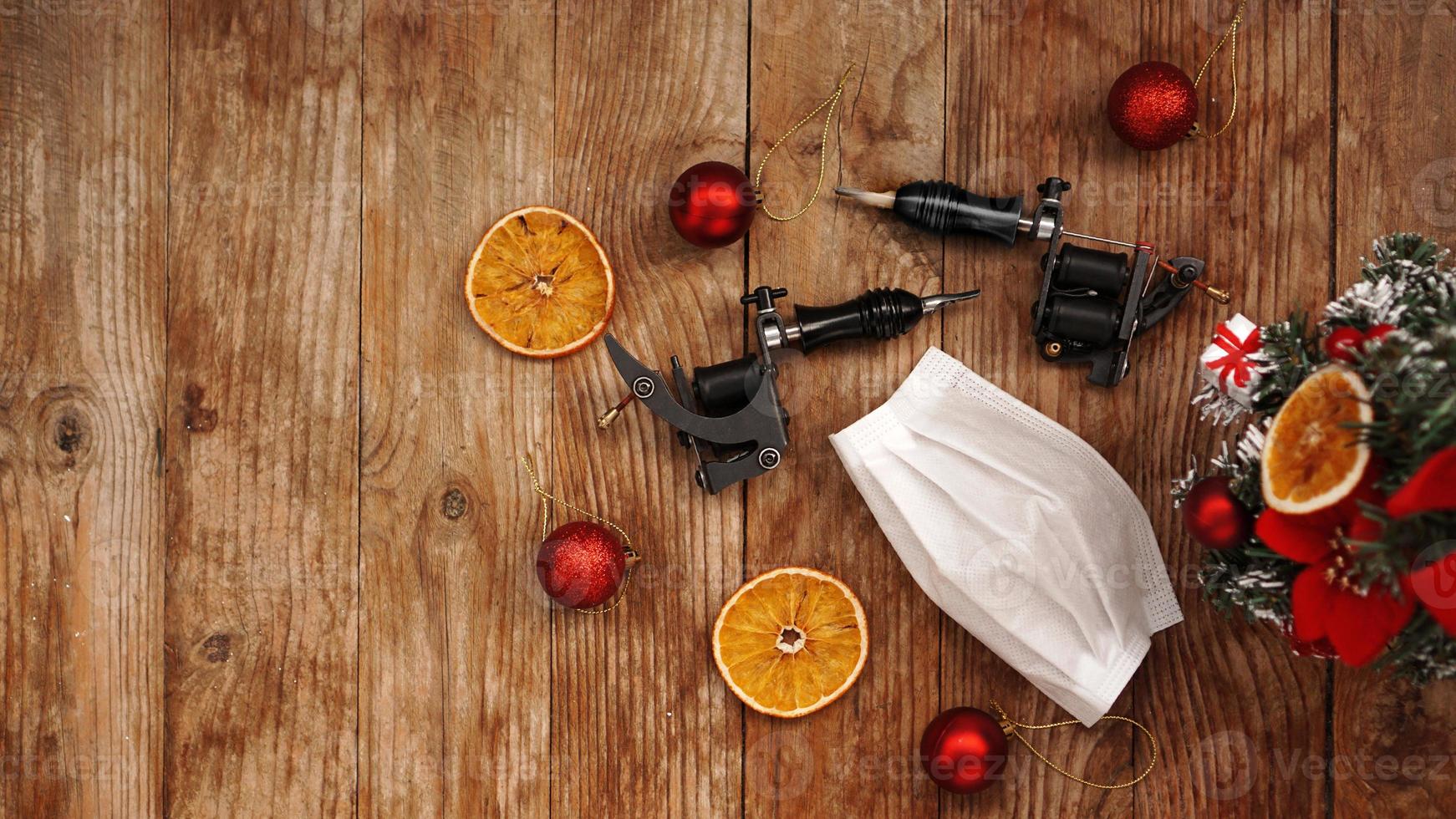 Tattoo machine with protectives face mask on a christmas background photo