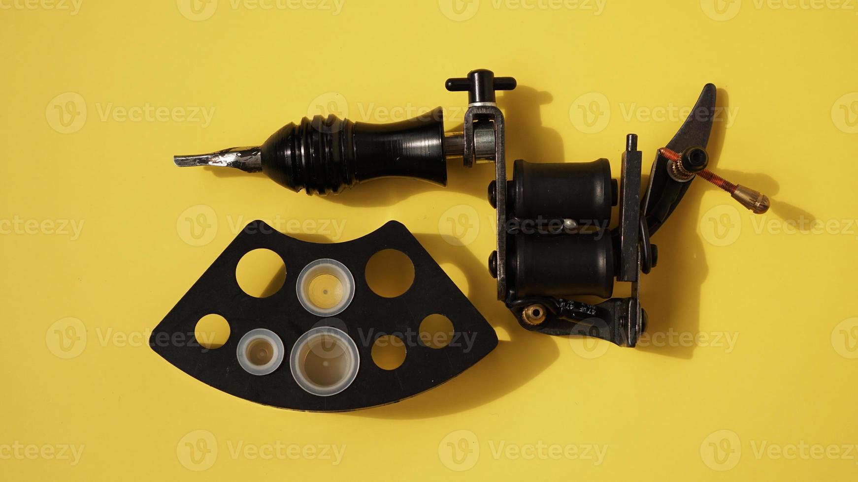 Tattoo equipment, tattoo ink plastic caps and tattoo machine on yellow photo