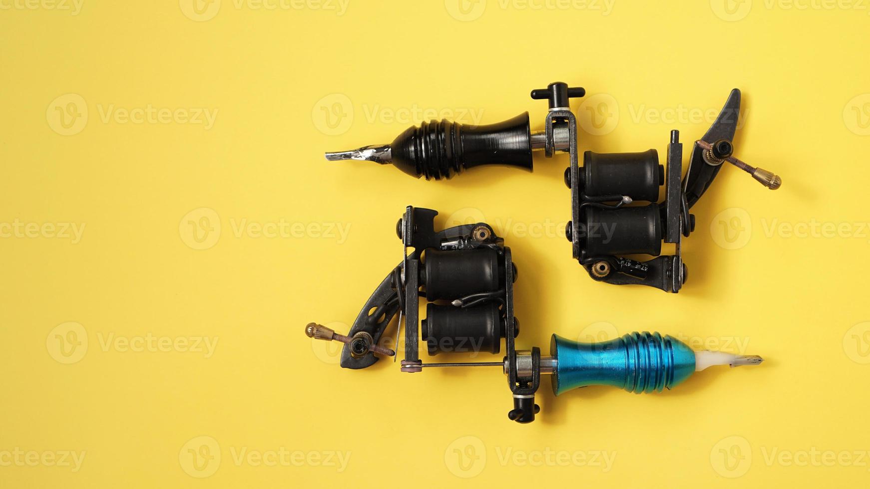 Two tattoo machines on a yellow background photo