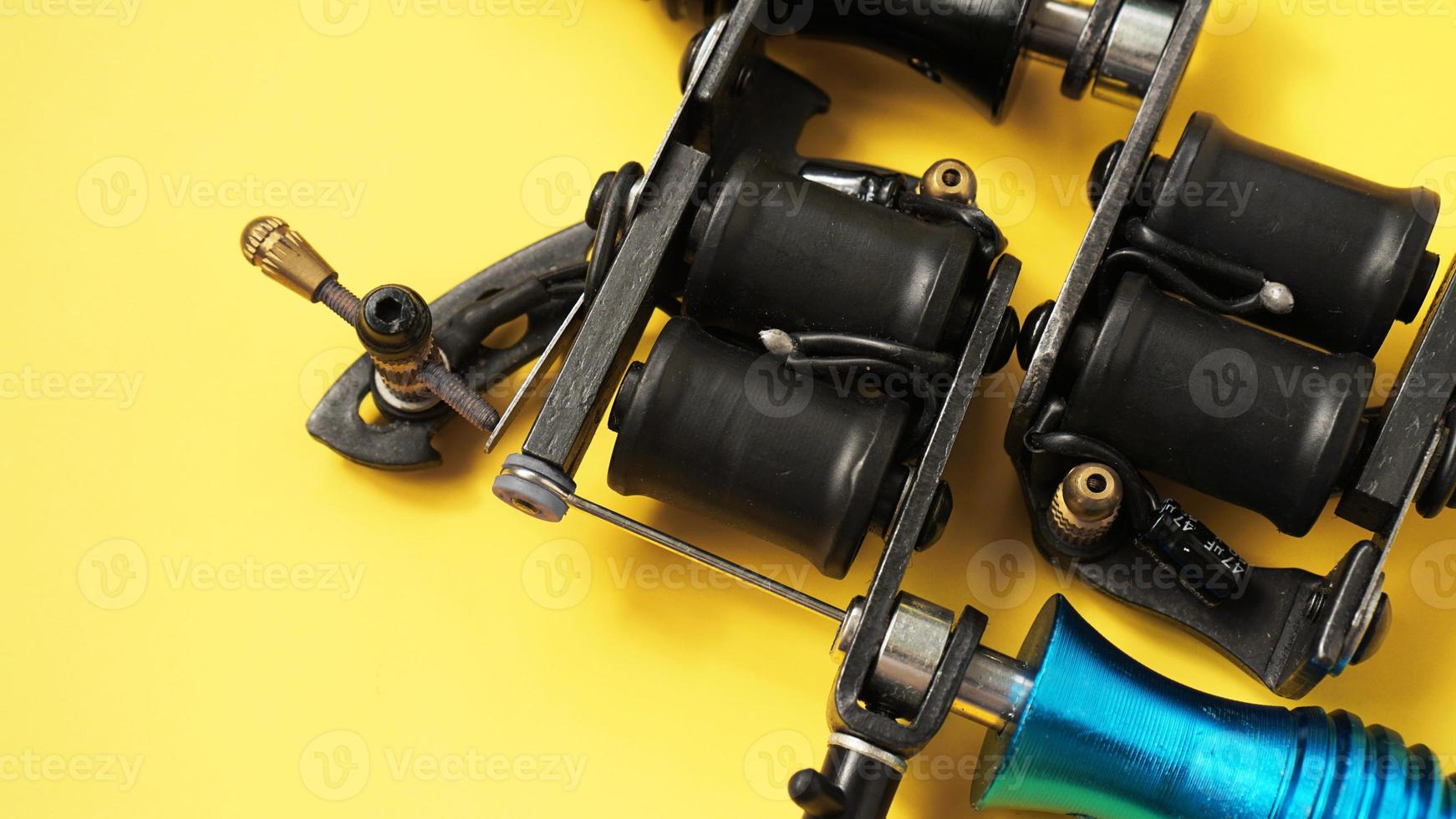 Two tattoo machines on a yellow background photo