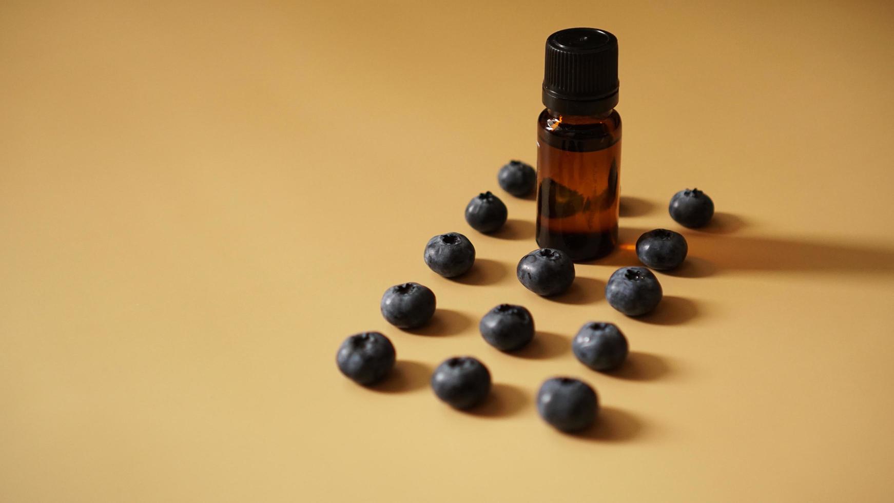 A bottle of blueberry seed essential oil and fresh blueberries photo