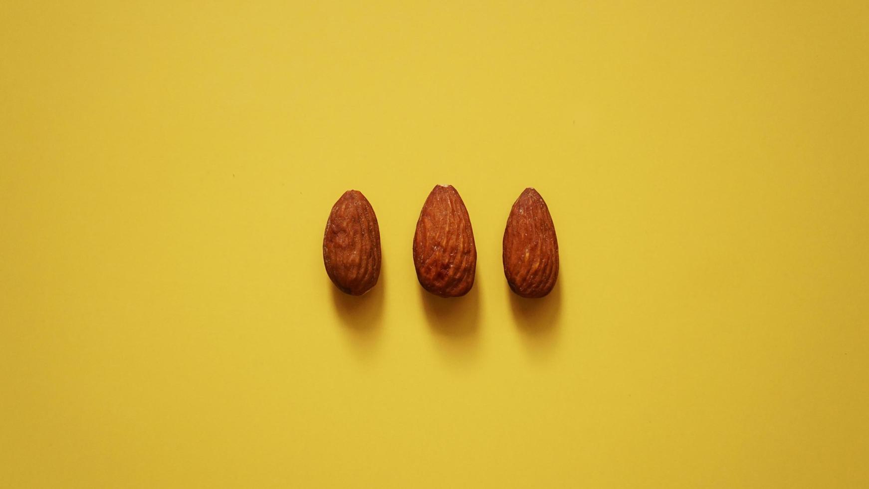 The three almonds on yellow background photo