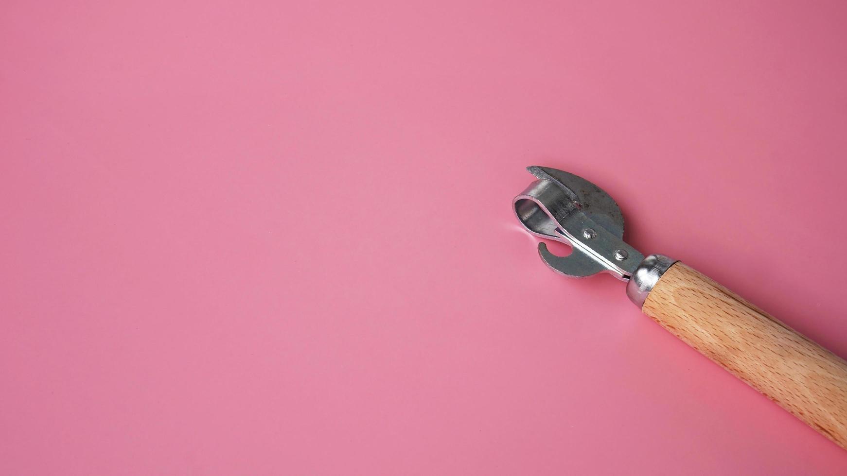 Wooden can opener on pink background photo