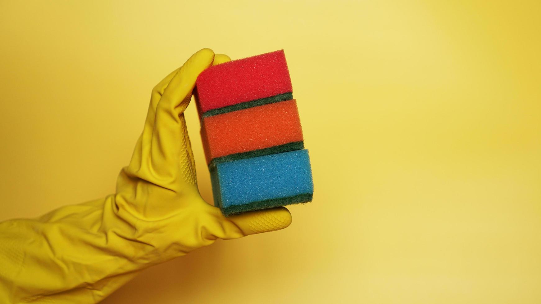 Hand in glove holding few washing sponges photo