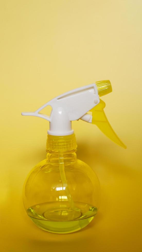 Spray bottle on yellow background photo
