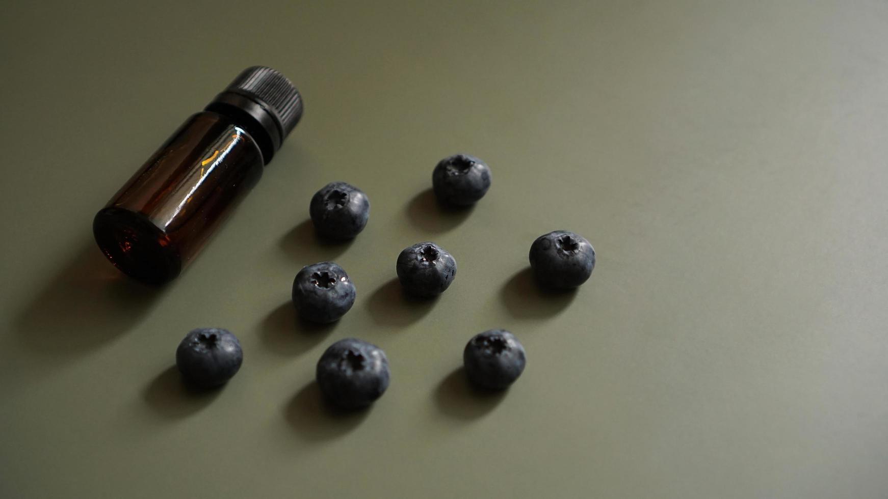 A bottle of blueberry seed essential oil and fresh blueberries photo