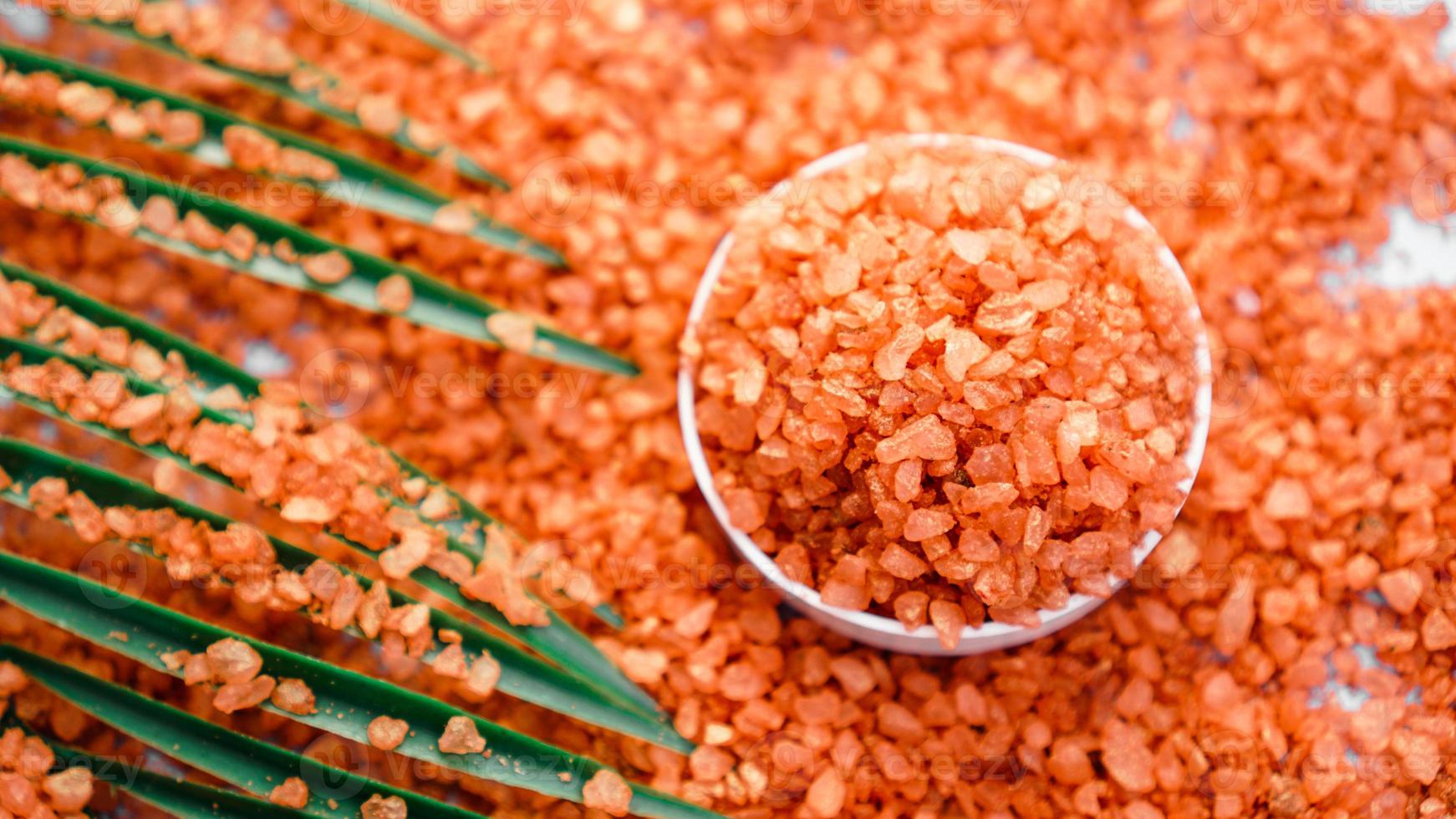 Orange sea salt on a white background. Tropical palm leaves photo