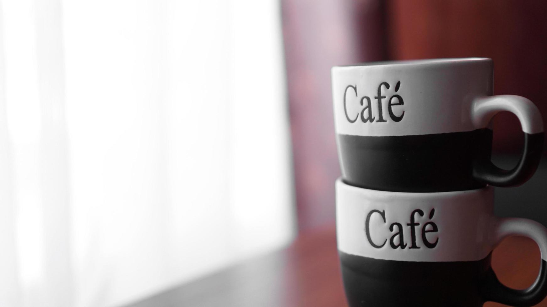 Two little coffee cups over a wooden table with a blurred background photo