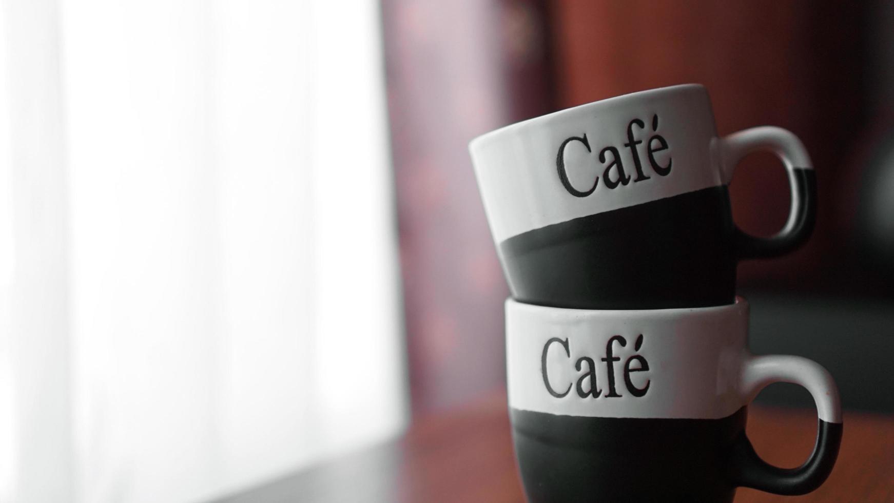 Two little coffee cups over a wooden table with a blurred background photo