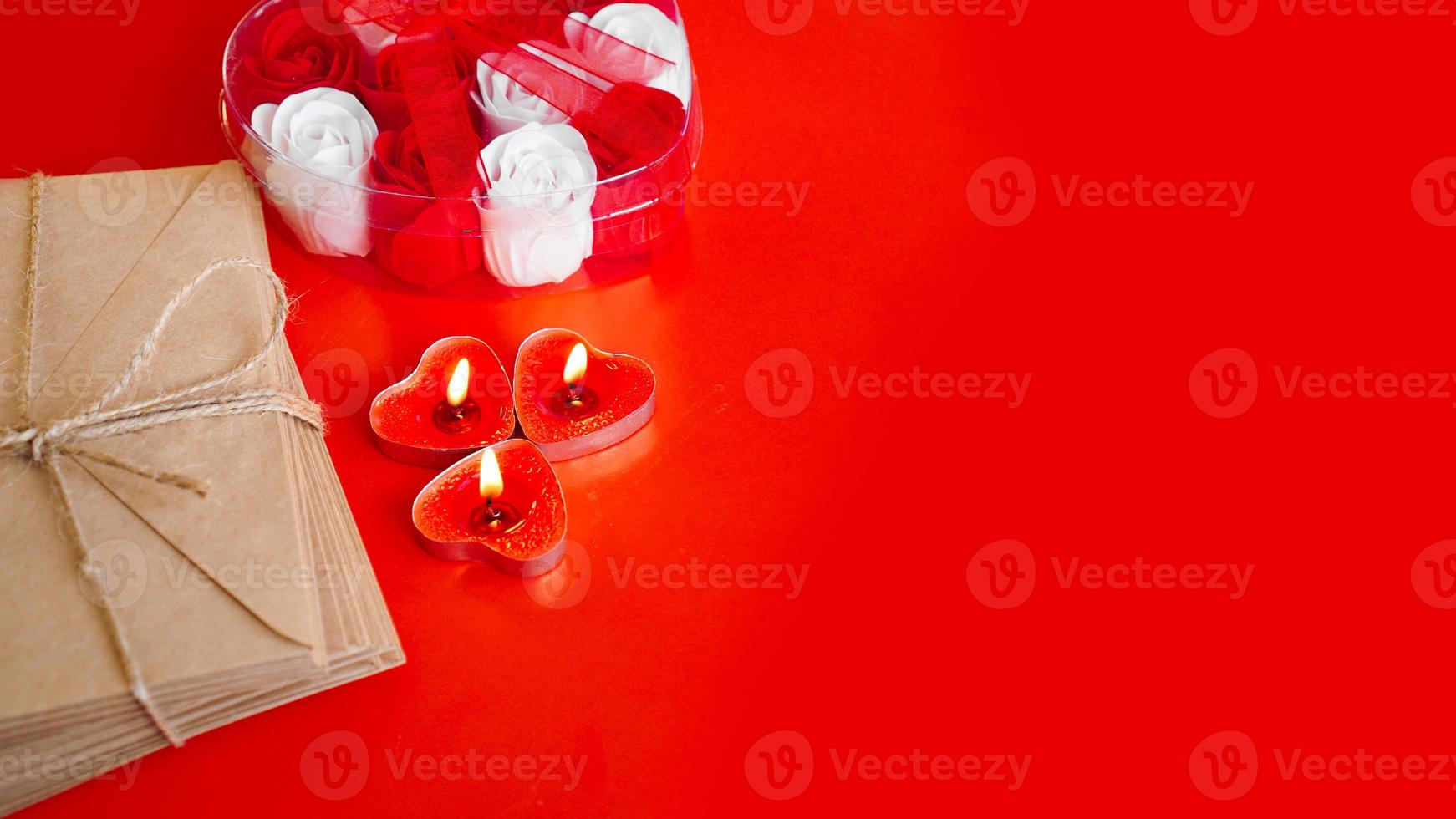 Kraft paper envelopes with red candles on a red background. photo