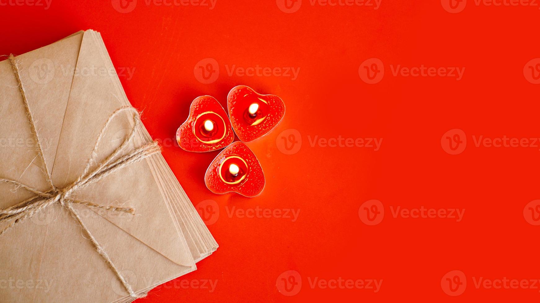 Sobres de papel kraft con velas rojas sobre fondo rojo. foto