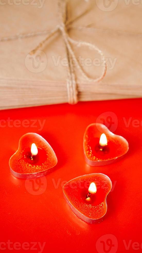 Sobres de papel kraft con velas rojas sobre fondo rojo. foto