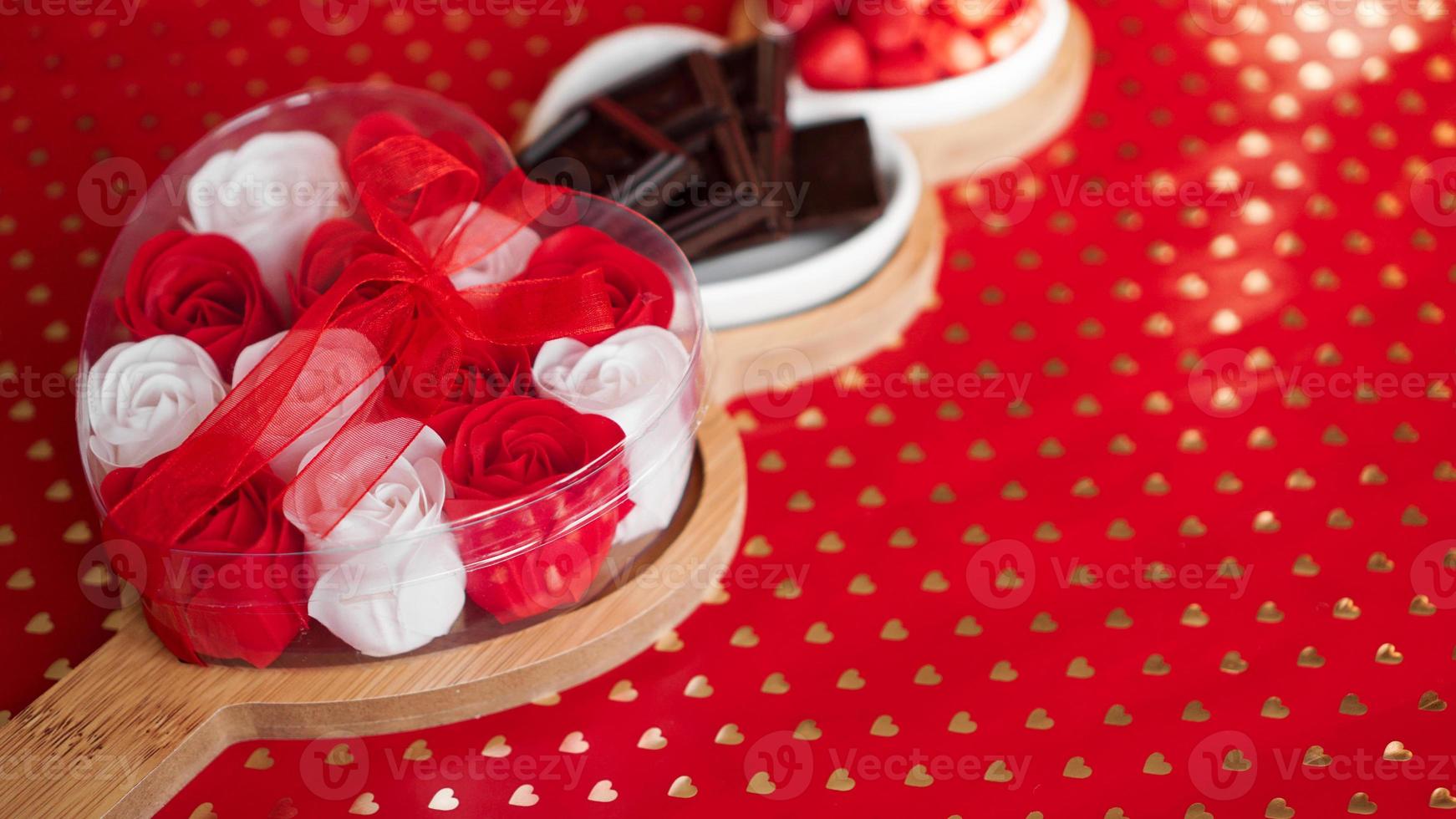 rosas, chocolates y dulces en un plato en forma de corazón foto