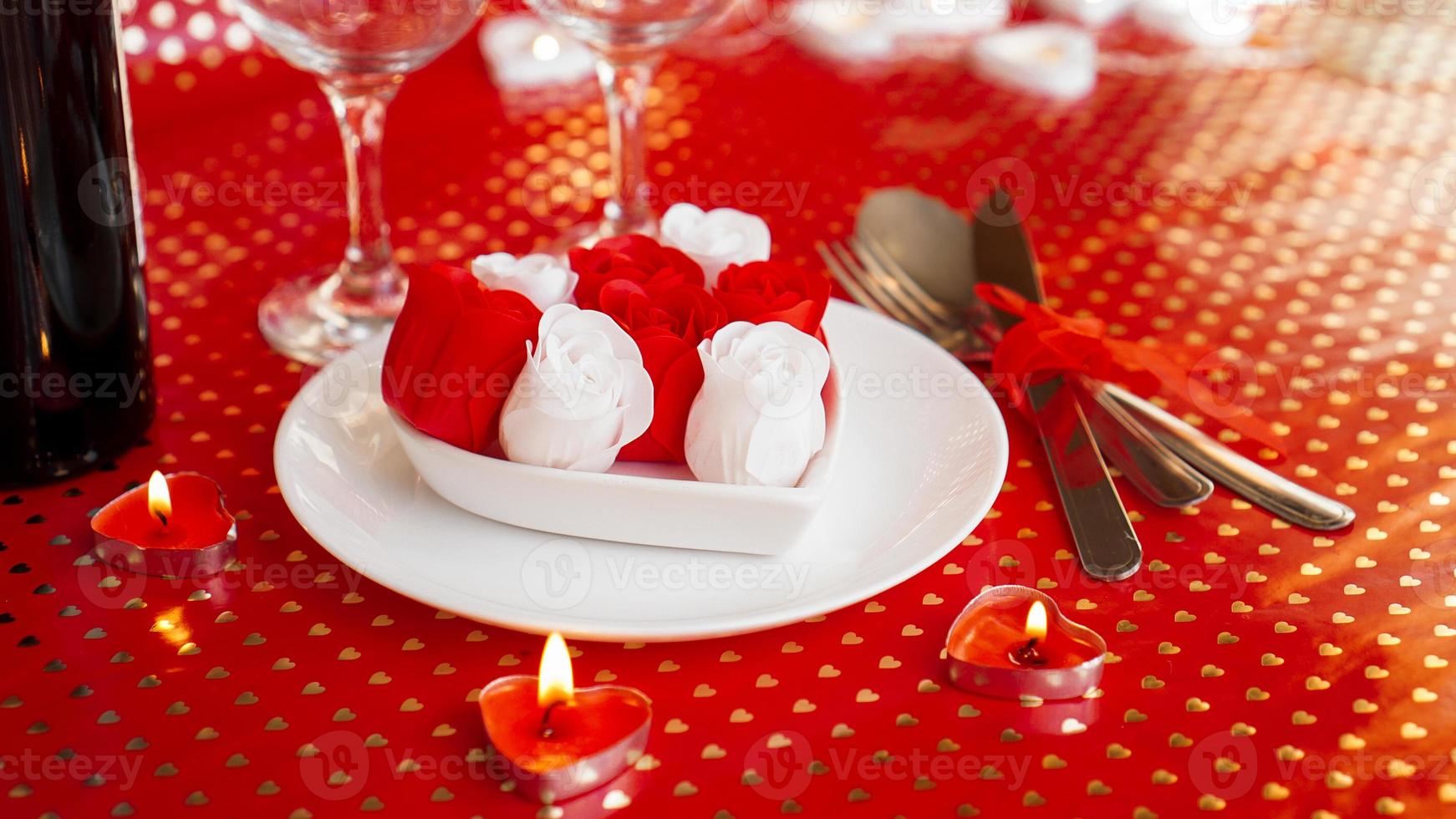 A white plate with wine, a knife and fork on a bright red background photo