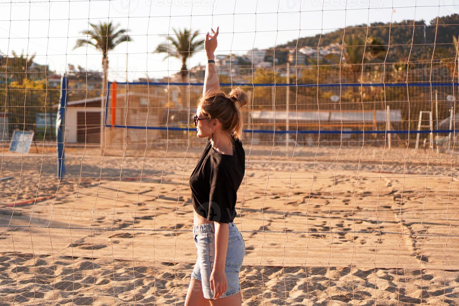 Retrato de mujer atractiva cerca de la red de voleibol en la playa. foto