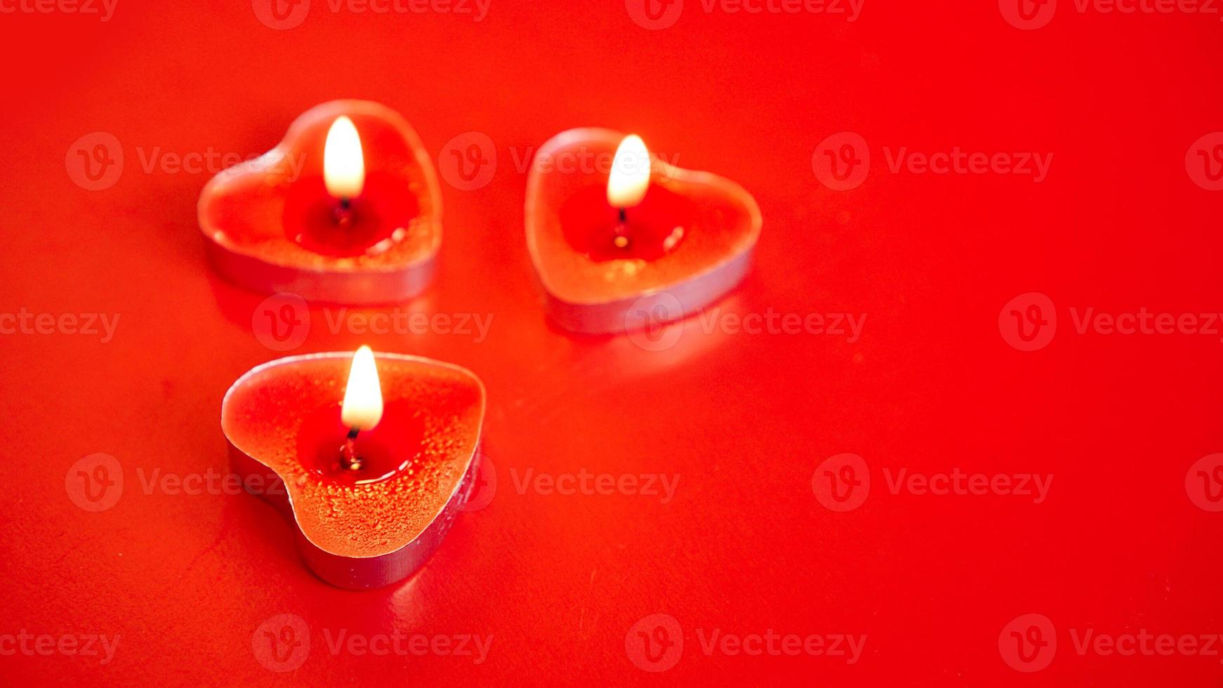 Three red burning candles with heart shaped photo