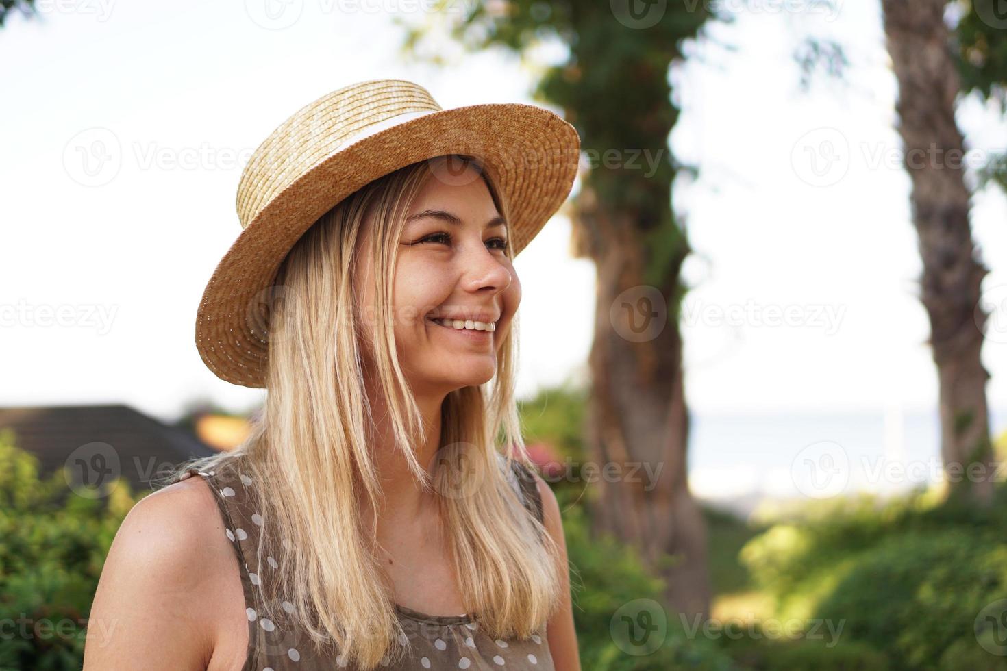 Portrait of a young blonde in a hat on a tropical background photo