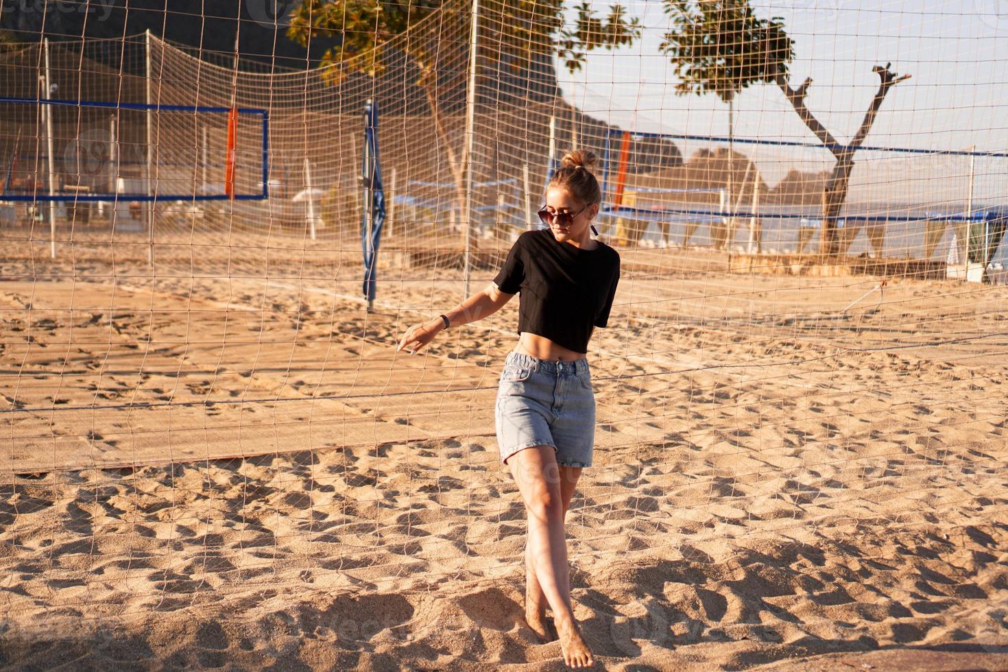 Retrato de mujer atractiva cerca de la red de voleibol en la playa. foto