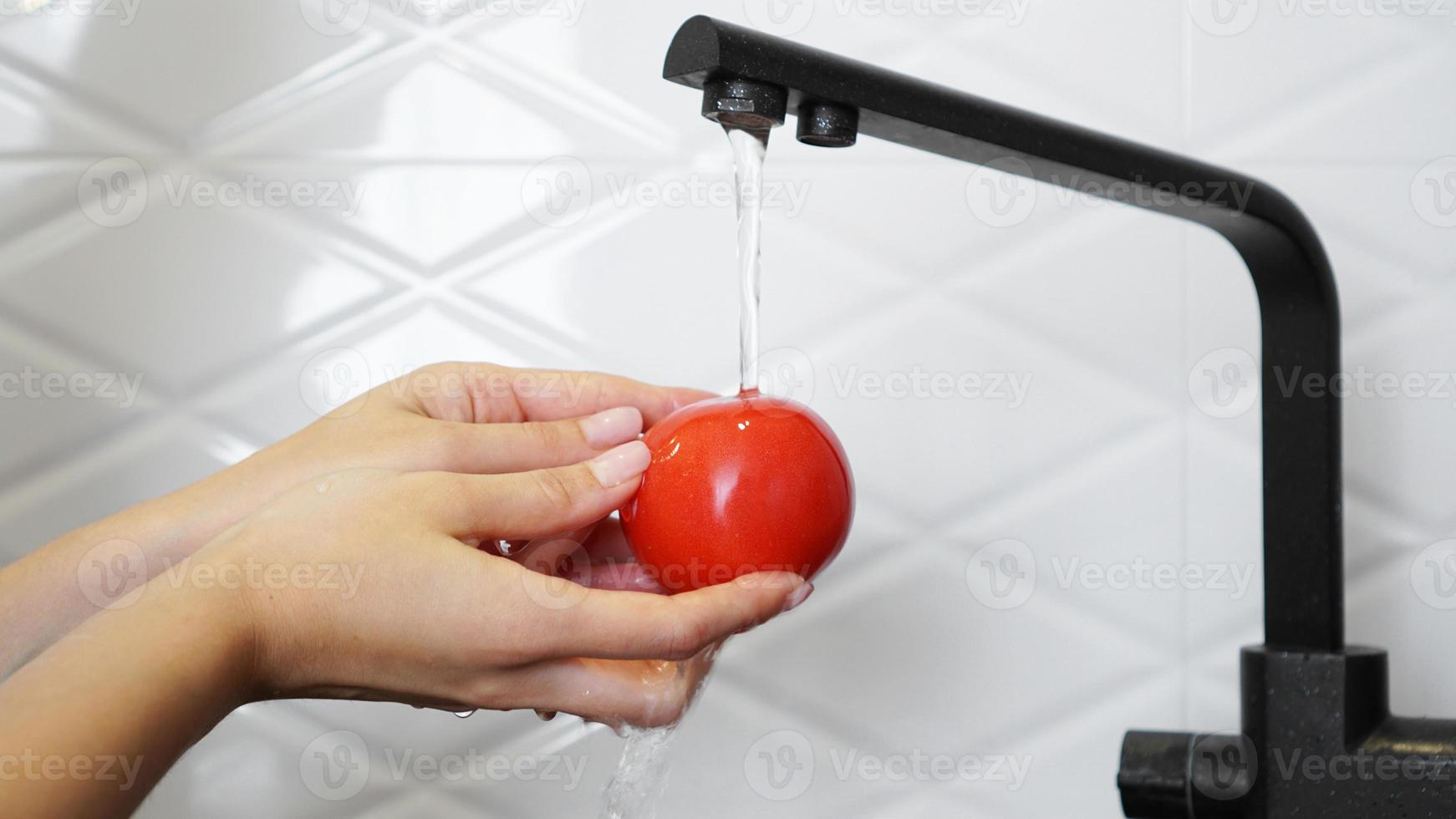 mujer lavando tomates y tomate en sus manos foto