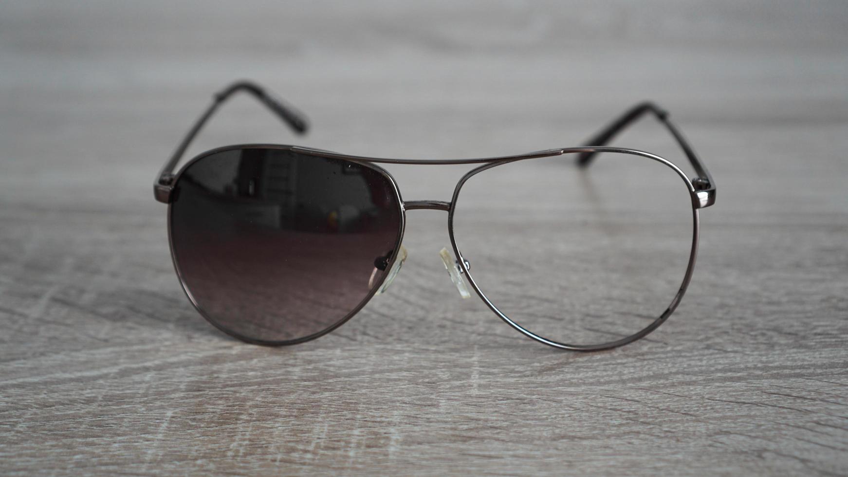 Broken sunglasses on grey wooden background photo